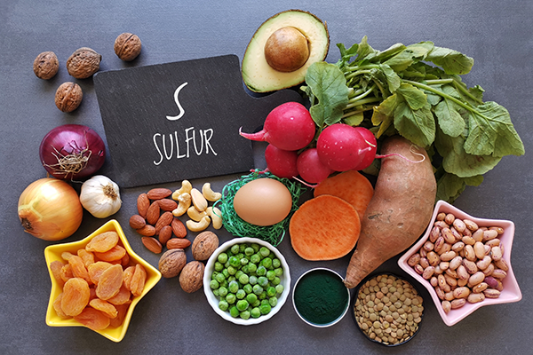 Fruits and vegetables on gray background in front of chalkboard sign that says 