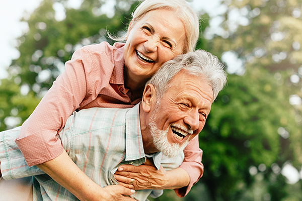Man giving a woman a piggyback ride in the park 