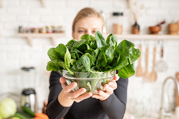 Woman holding spinach, calcium concept