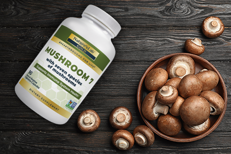 mushroom supplement next to bowl of mushrooms on wooden background
