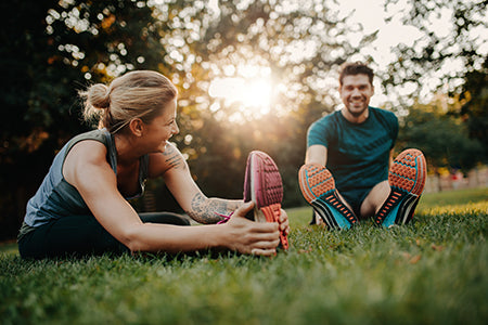 couple working out, stretching outdoors in park