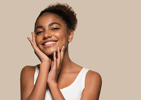 young woman smiling with hands near face, glowing skin concept