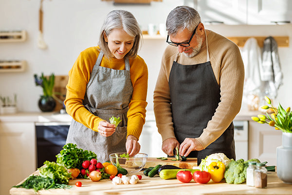 Mature couple chopping vegetables in the kitchen