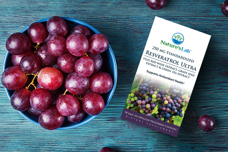 Nature's Lab Resveratrol Ultra and grapes on blue wooden background