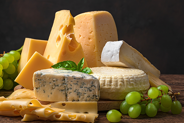 Assortment of cheese high in vitamin k2 on a wooden table with green grapes