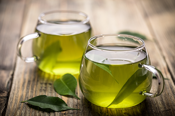 Cup of green tea with fresh tea leaves