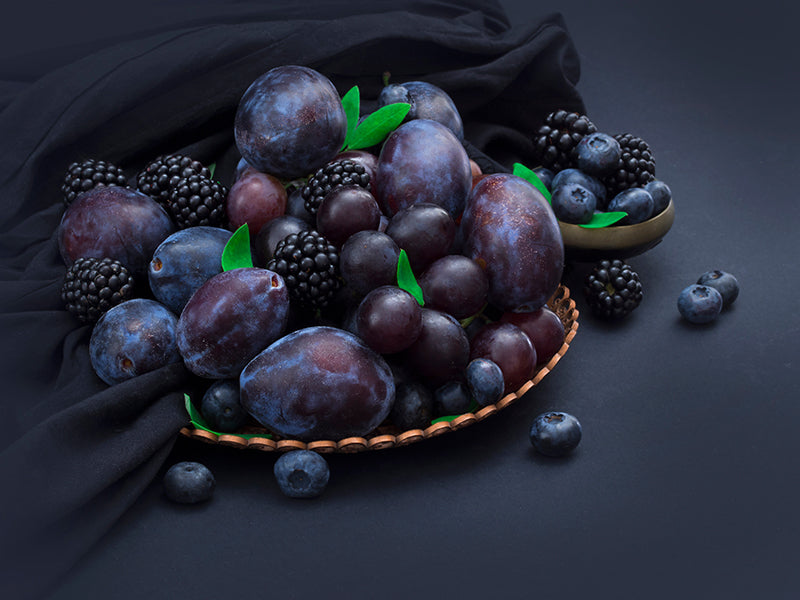 composition featuring berries and grapes on a table with purple hues