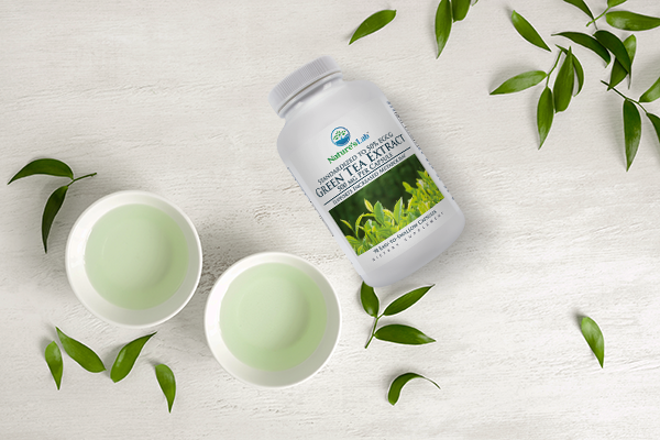 green tea extract supplement next to leaves and cups of tea