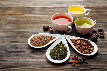 Assortment of green tea leaves and other types of tea on wooden table