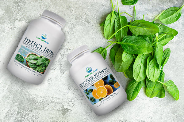 Nature's Lab Perfect Iron and Iron Plus Vitamin C on countertop next to pile of spinach