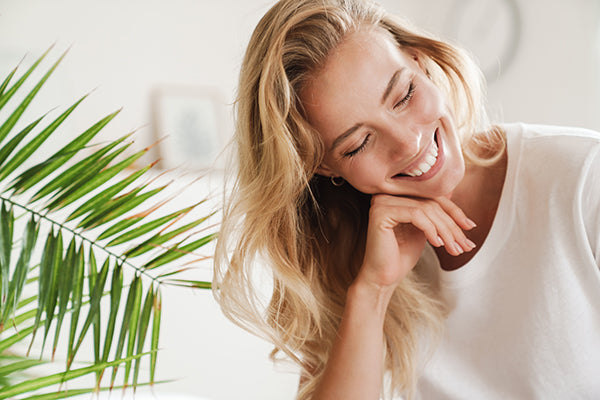 Female smiling, stress-free with palm leaf background