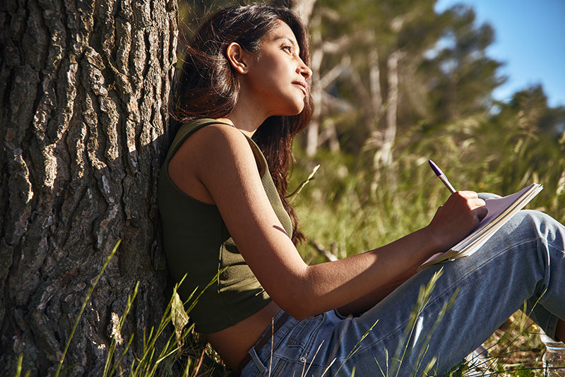 Woman writing in journal outdoors