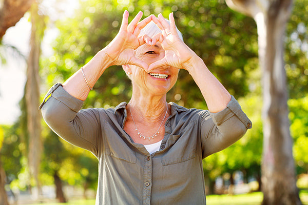 Woman making heart shape with hands near face